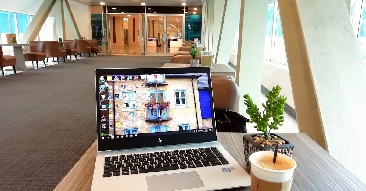 Contemporary office lounge featuring a laptop, coffee cup, and plant on a table with stylish interior design.