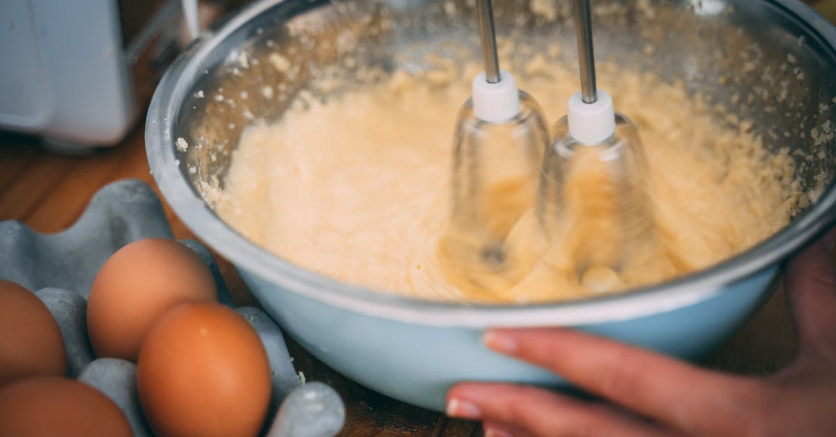 Close-up of batter being mixed in a bowl with eggs nearby on a wooden table.