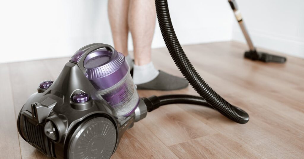 Crop anonymous male tiding flat with modern wireless vacuum cleaner while doing housework
