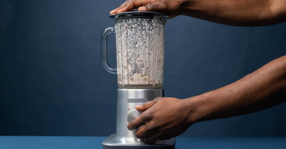 Close-up of male hands operating a blender in a kitchen setting.