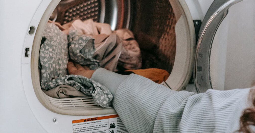 Crop unrecognizable female loading various dirty clothes in modern white washing machine during laundry routine in light room at home